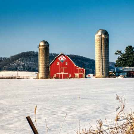 red and white barn house on snow covered ground under blue sky